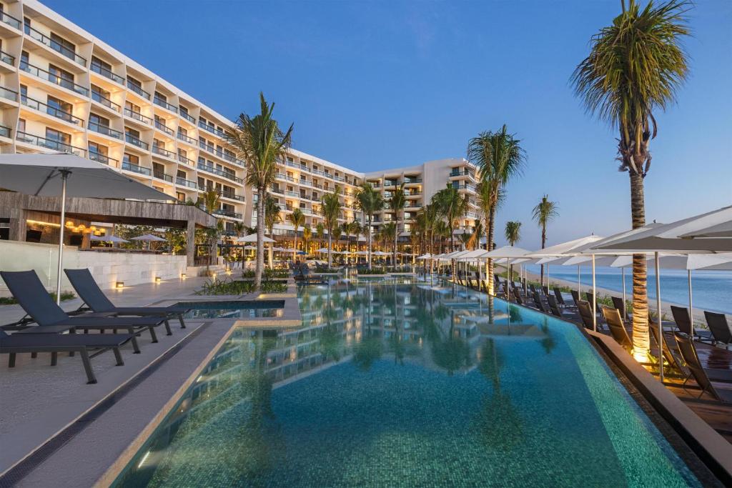 a pool at a resort with chairs and palm trees at Hilton Cancun, an All-Inclusive Resort in Cancún