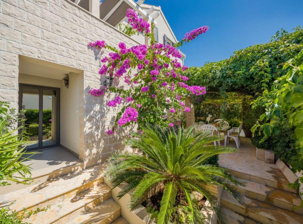a house with purple flowers on the side of it at Apartment Oaza in Supetar