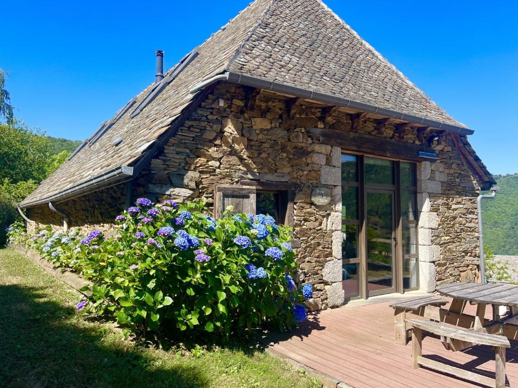 a small stone building with a bench and flowers at LA PERLE DE LA VALLÉE in Montézic