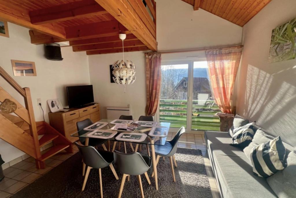 a dining room with a table and chairs and a couch at Cozy apartment with lake view in Gérardmer