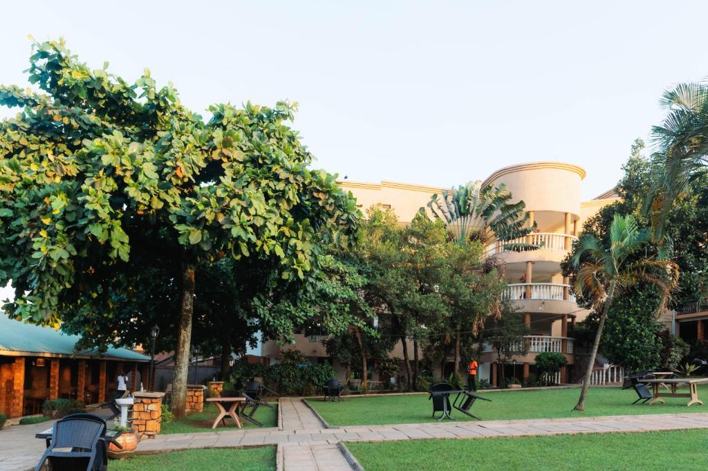 a building with a park with benches and trees at Kampala Kolping Hotel in Kampala