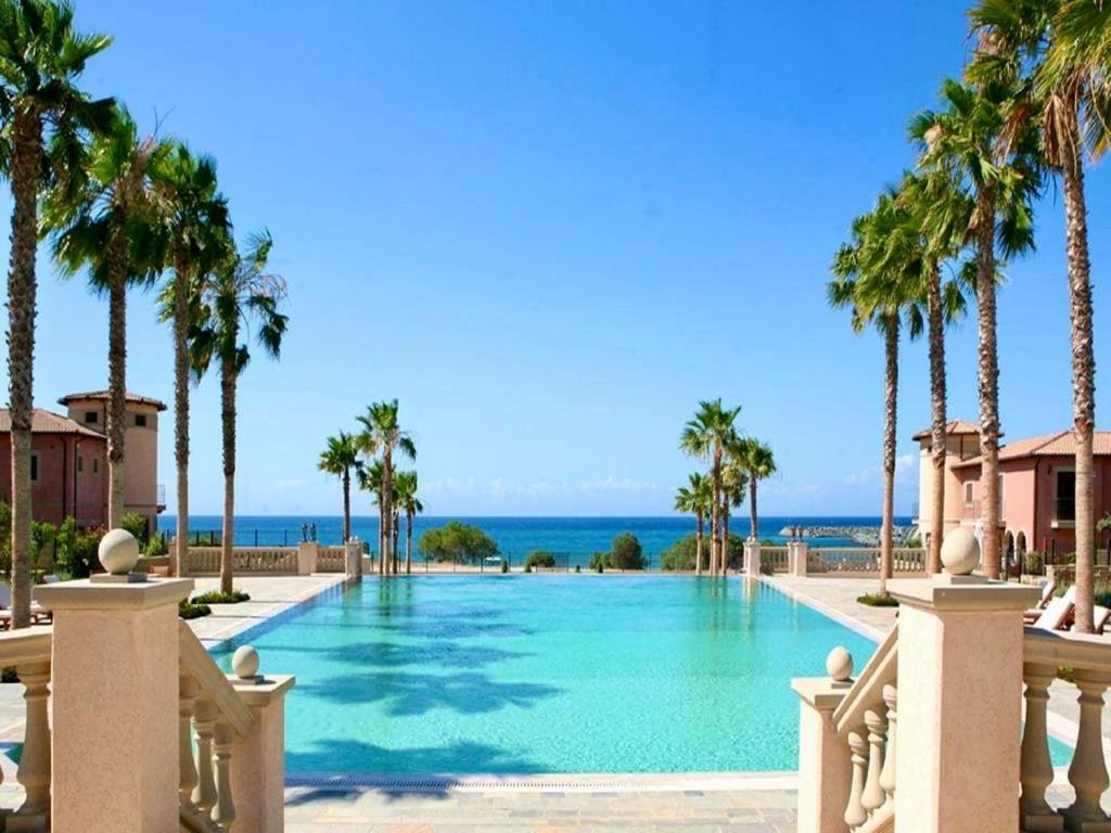 a swimming pool with palm trees and the ocean at The Amathountas Residence in Pyrgos