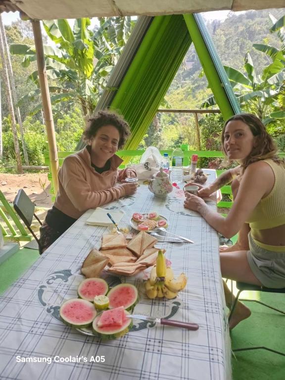 two women sitting at a table with fruit on it at Ella Cool Air Cabana in Ella
