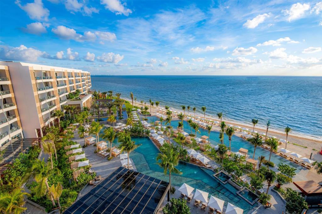 Oceanfront resort with palm-lined infinity pool, sun loungers, private cabanas and beachfront villas with direct sea access at Waldorf Astoria Riviera Maya in Cancún