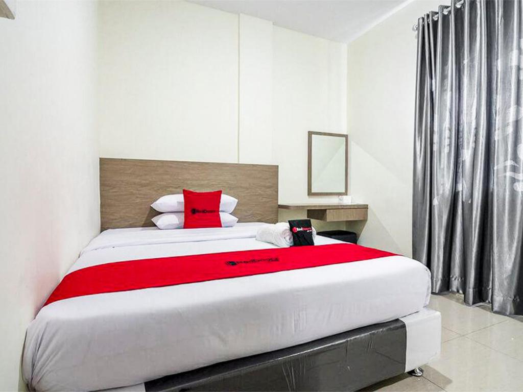 a bedroom with a large bed with red pillows at RedDoorz @ Baloi Batam in Batam Center