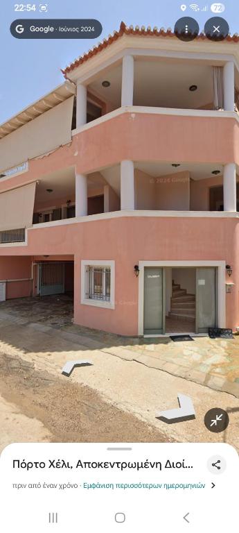 a large pink building with a garage in front of it at Στης Χαράς in Porto Heli