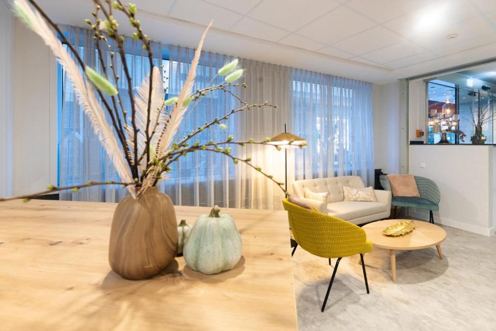 a living room with a table and a vase with flowers at Garner Hotel Cologne - Engelbertz by IHG in Cologne