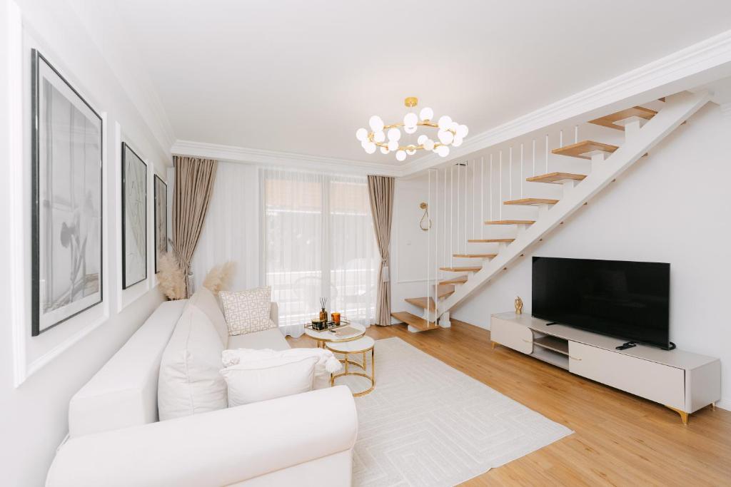 a white living room with a white couch and a tv at The Loft in Sovata