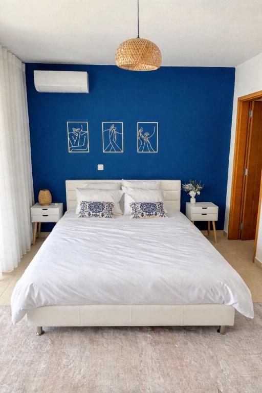a bedroom with a blue wall and a white bed at Apartamento Paradise beach in Prainha