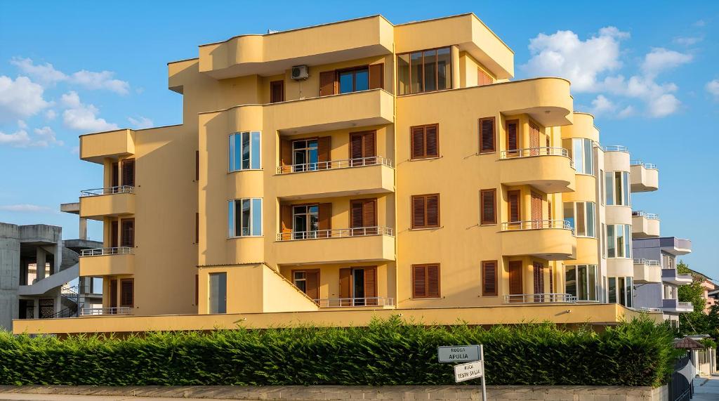a yellow building with balconies on the side of it at Apartments Vila Cala in Durrës