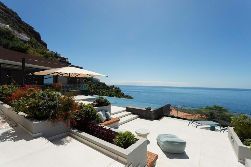 a patio with a view of the ocean at Villa Anjos - Luxury Villa with Infinity Pool & Ocean View in Canhas