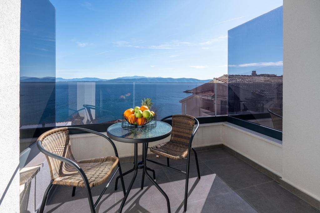 a table and chairs on a balcony with a view of the water at Wind Rose Bura-beachfront in Igrane