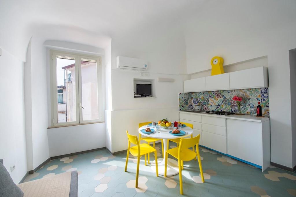 a kitchen with a table and two yellow chairs at La mia casetta al mare in Minori