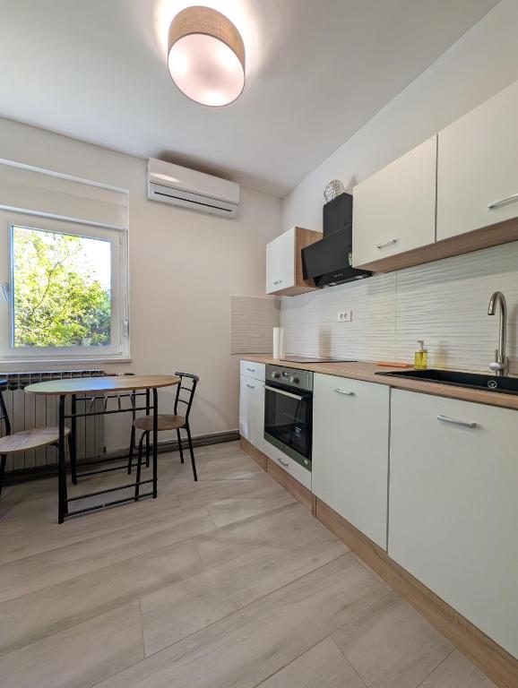 a kitchen with white cabinets and a table and a window at Bright & Sunny Studio in Sesvete