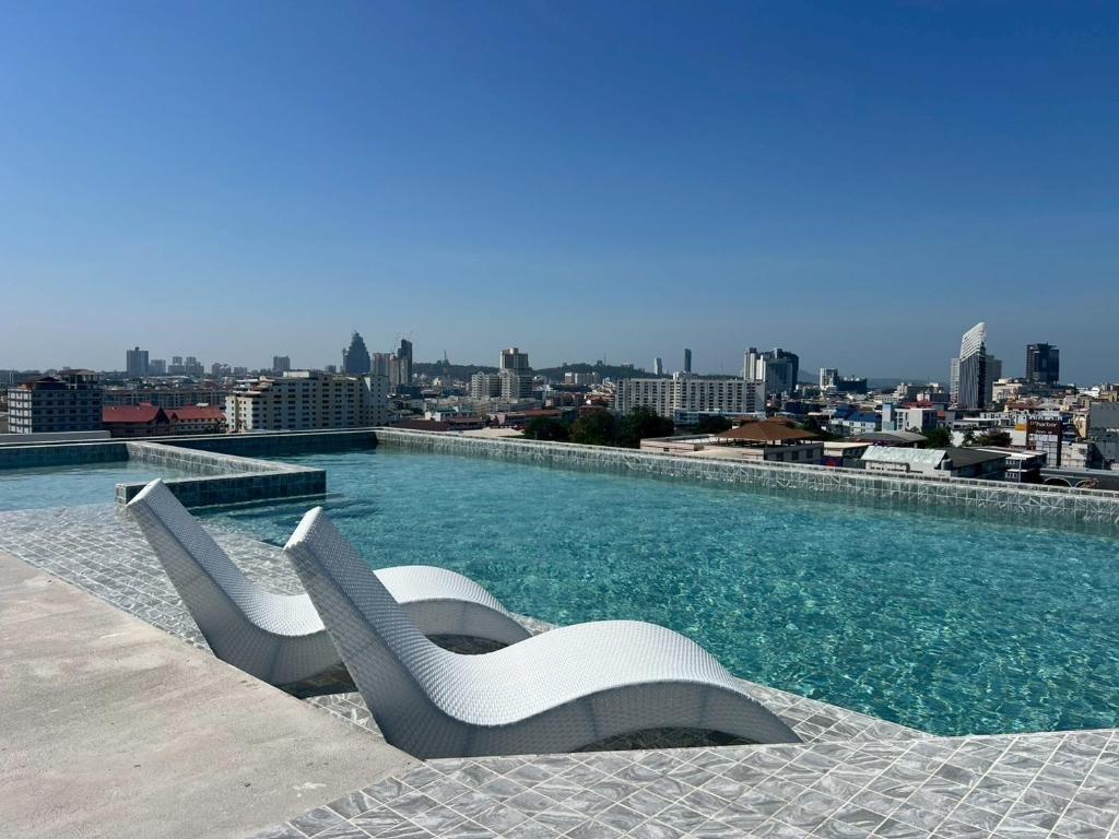 a pool with two white chairs on top of a building at The Iconic in Pattaya
