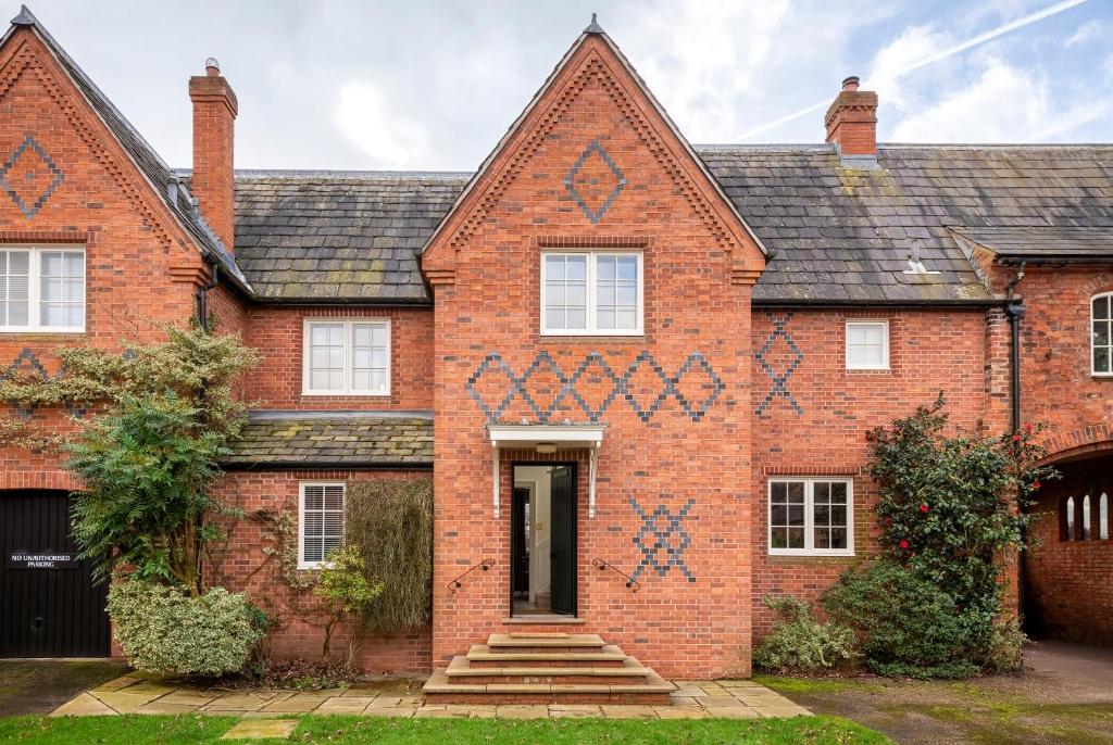an old brick house with blue crosses on it at West House in High Legh