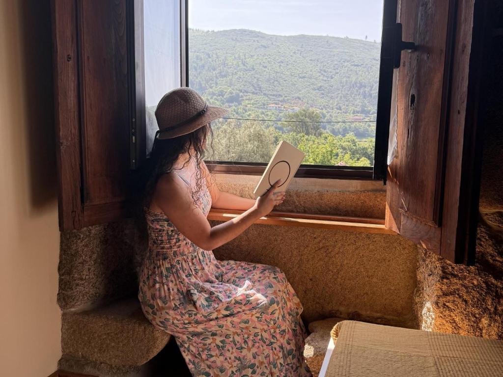 a woman sitting on a window sill reading a book at Serena Nest 01 in Rio Douro