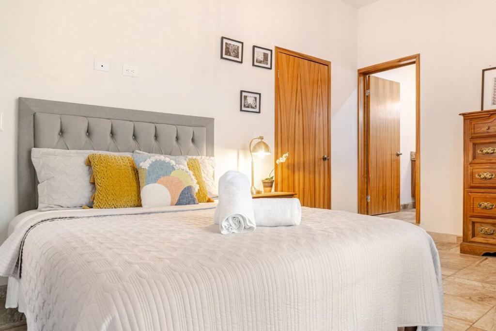 a bedroom with a large white bed with yellow pillows at Departamento privado 12 min Malecón in La Paz