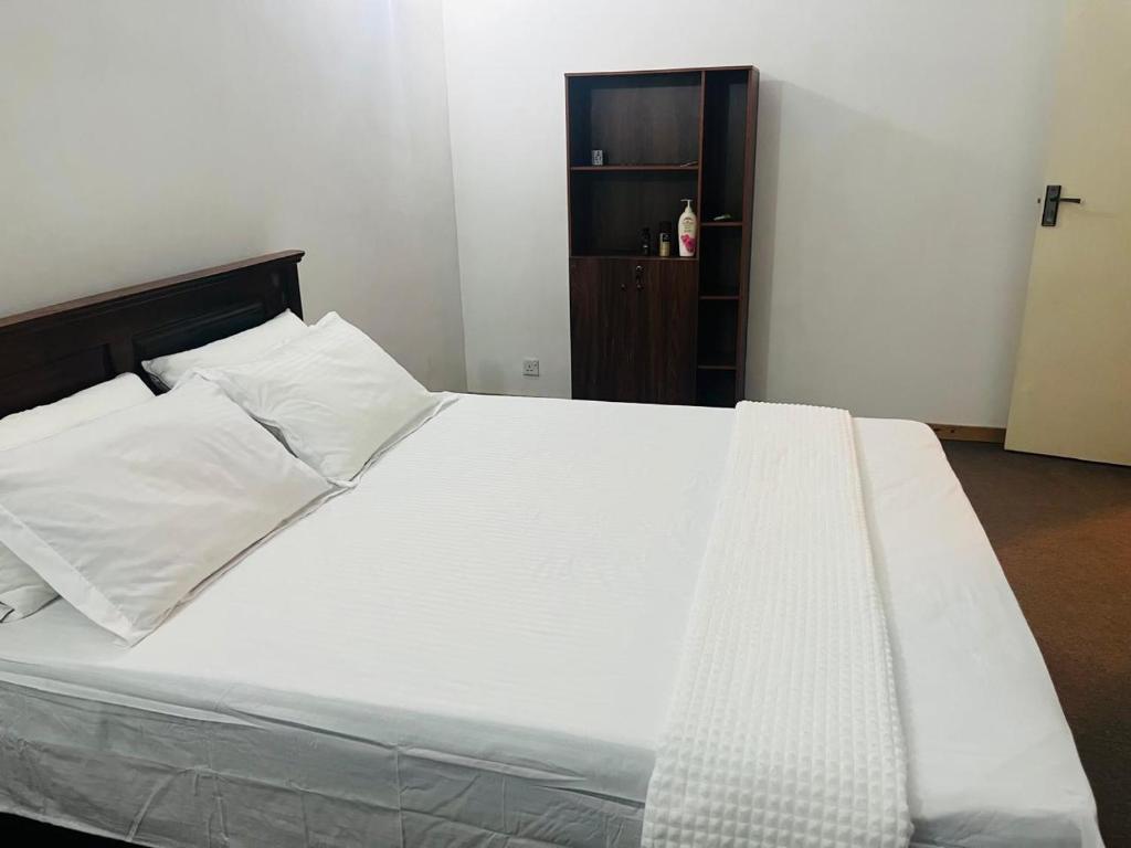 a bed with white sheets and pillows in a bedroom at Ceylon Airport Apartment in Raddoluwa