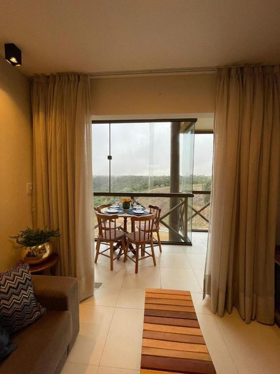a living room with a table and chairs and a large window at Apartamento aconchego na Serra in Bananeiras