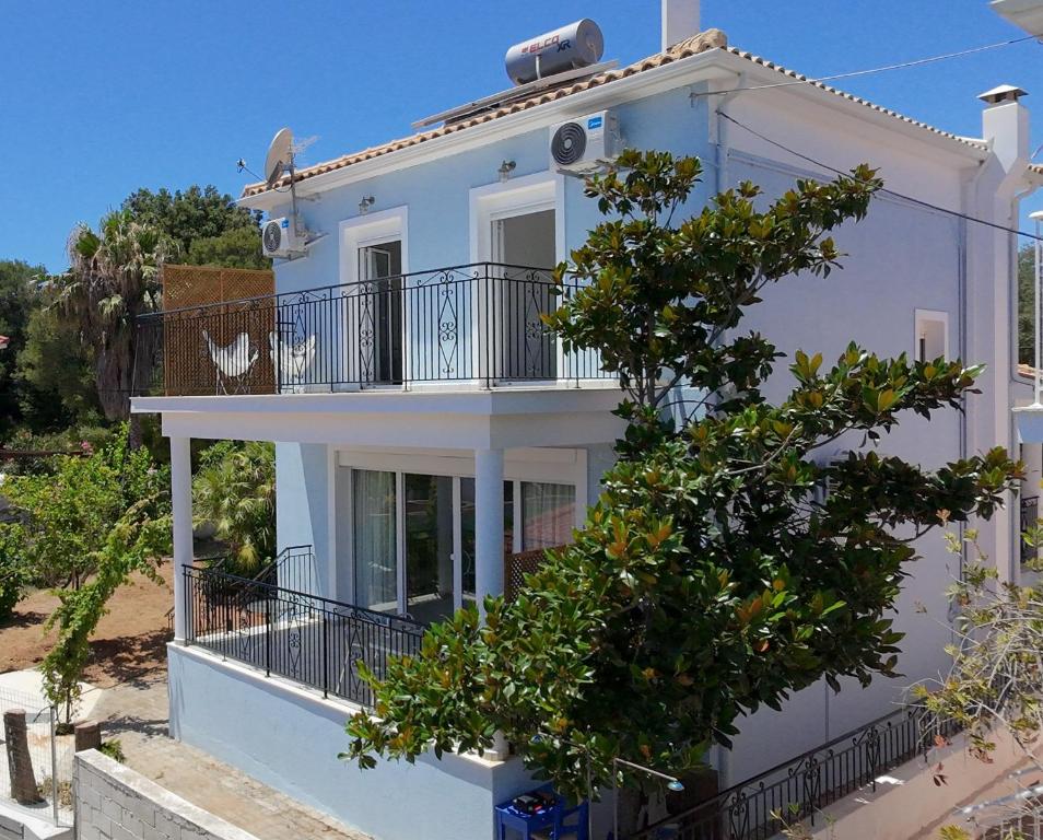 a white house with a tree in front of it at Aquarius Kefalonia in Pesádha