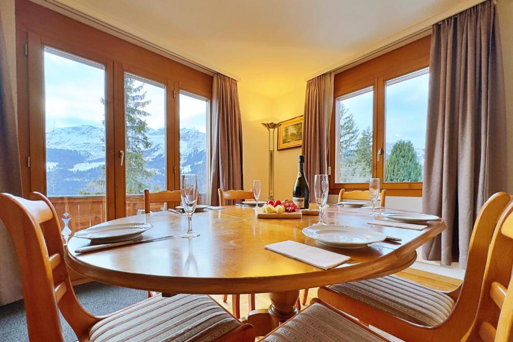 a dining room with a table with chairs and windows at Chalet Miravalle 3 in Wengen