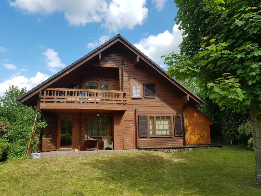 a log house with a deck on a lawn at Chalet am Silbersee in Frielendorf