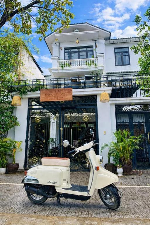 a white scooter parked in front of a house at Pavillon D'Hue Homestay in Hue