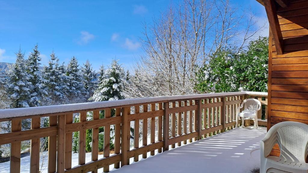 a wooden deck with two chairs and snow on it at Chalet Masana in Murat-le-Quaire