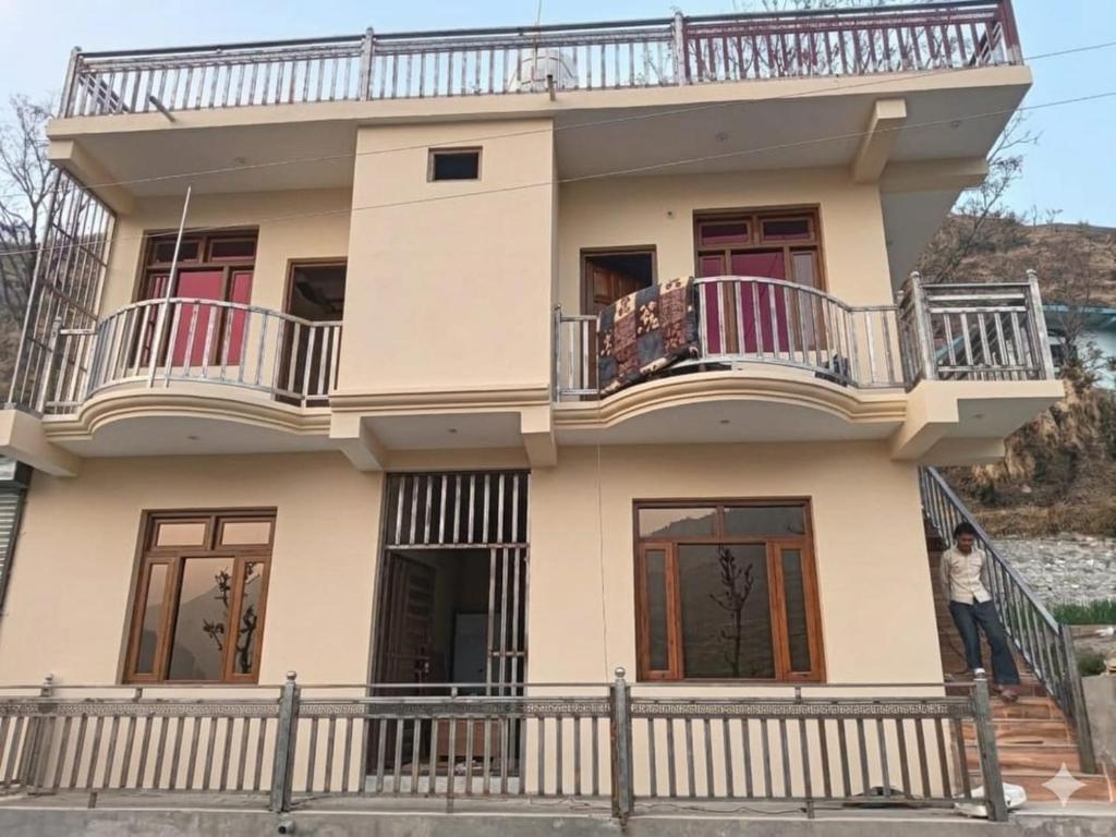 a man standing on the balcony of a house at Hotel tapobhumi in Barkot