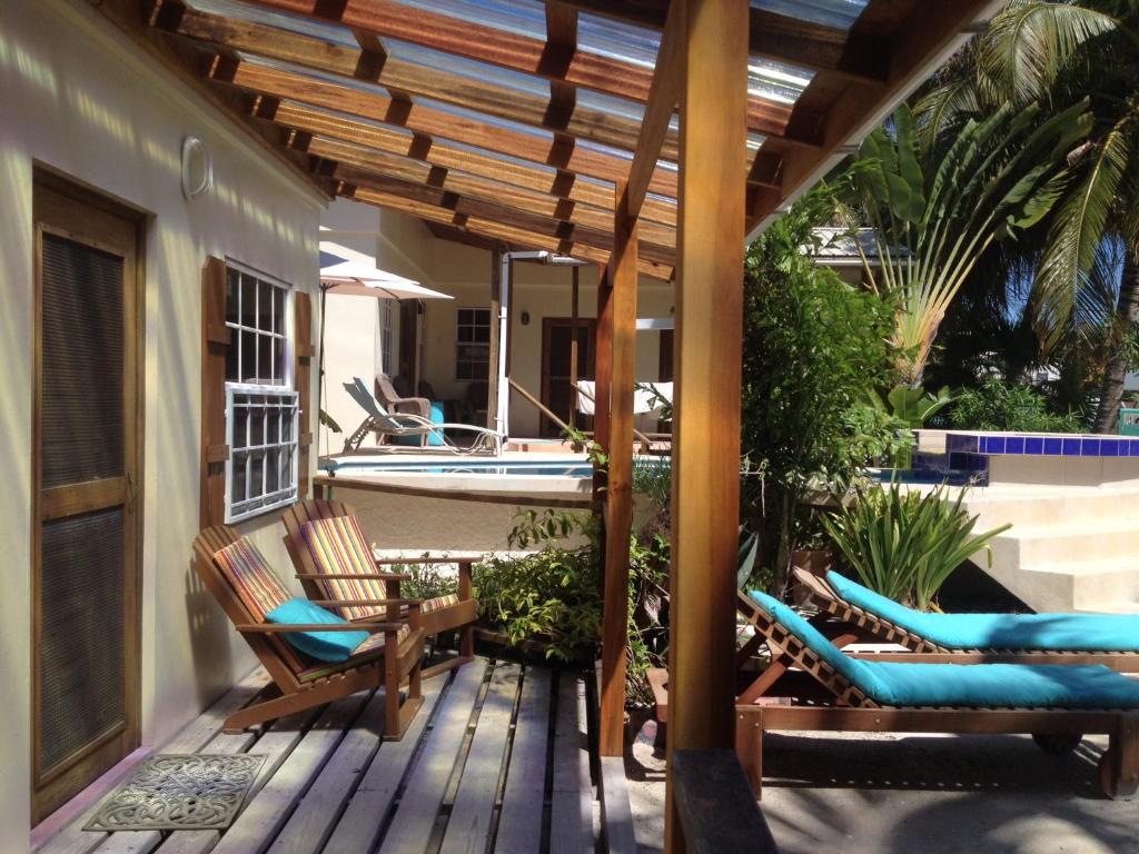a porch with chairs and a deck with a boat at Amanda's Place Green Studio - pool and tropical garden in Caye Caulker