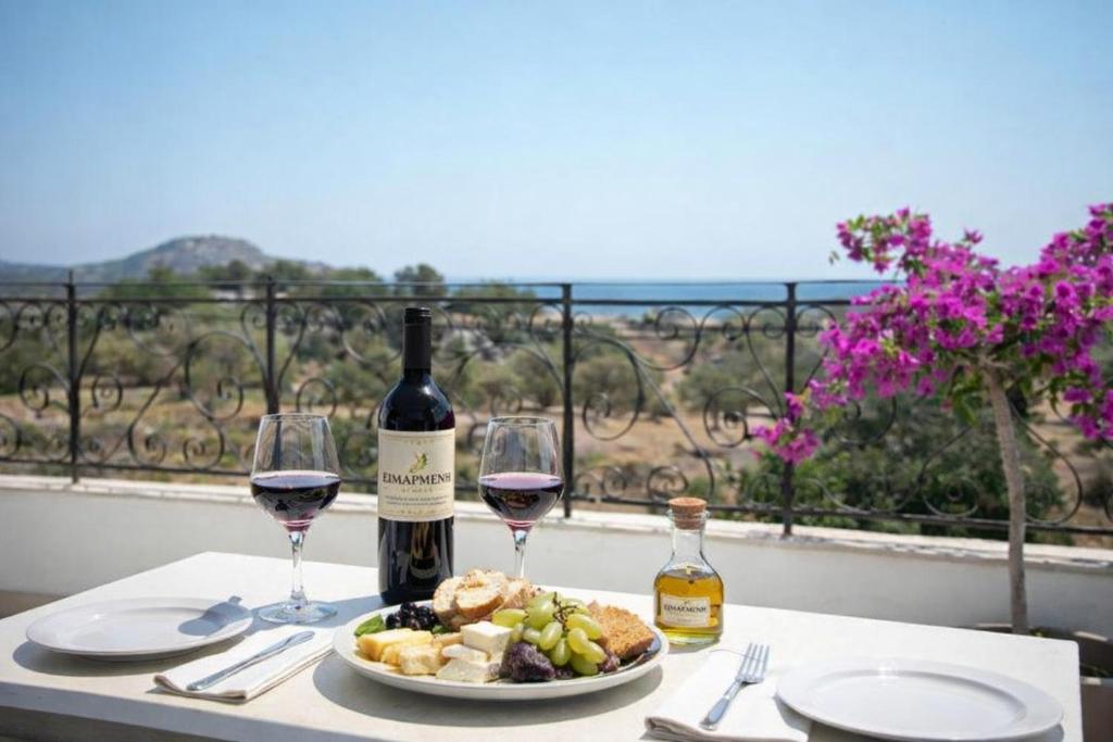 a table with a plate of food and two glasses of wine at Exclusive Olive & Herb Villa, Mountain to Sea Views, Rhodes in Afantou