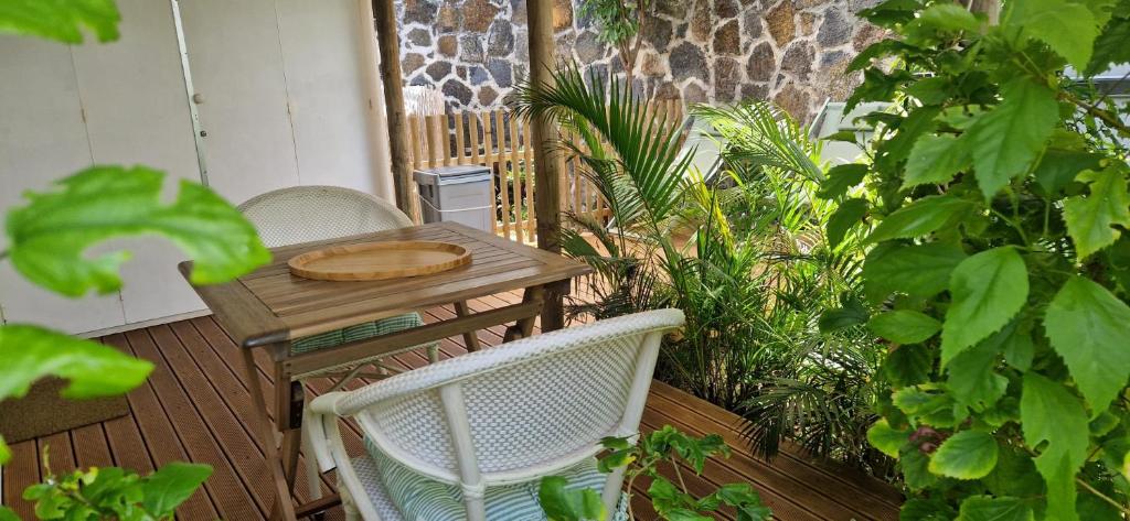 a wooden table and chairs on a deck with plants at Tikaban in Pointe d'Esny
