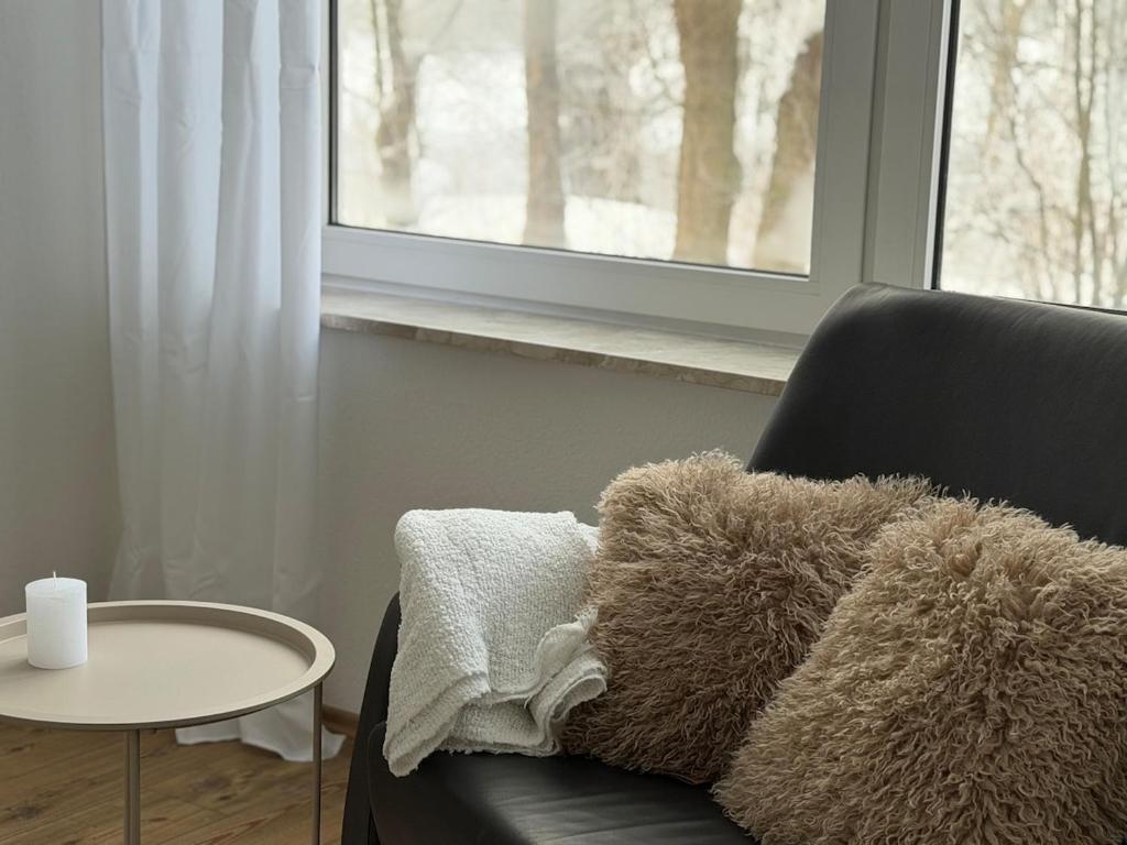 ein Wohnzimmer mit Sofa, Tisch und Fenster in der Unterkunft Deich Kate in Wurster Nordseeküste