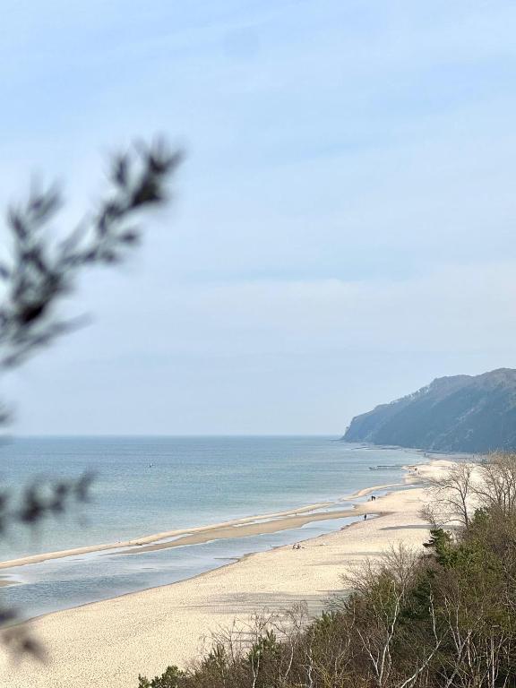 a beach with people on the sand and the water at Baltic Infinity Suite 413 - SPA & Pool Access in Międzyzdroje