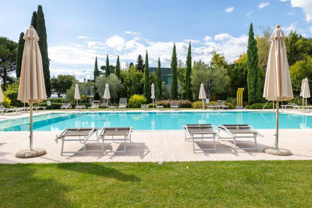 a pool with chairs and umbrellas in a yard at Corte Fasanella 25 - Gardagate in Toscolano Maderno
