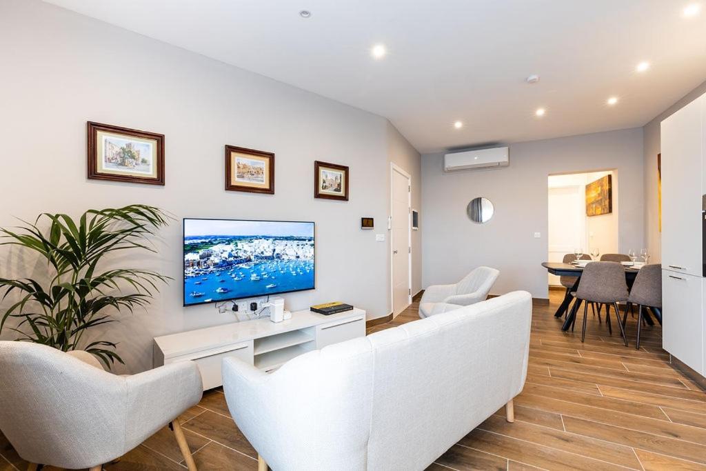 a living room with a couch and a tv on a wall at V86 - Charming 1 Bedroom Isla Duplex Apt with Harbour Views in Senglea