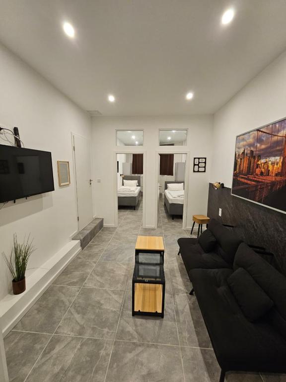 a living room with a black couch and a tv at ApartHotel Slumber in Geesthacht