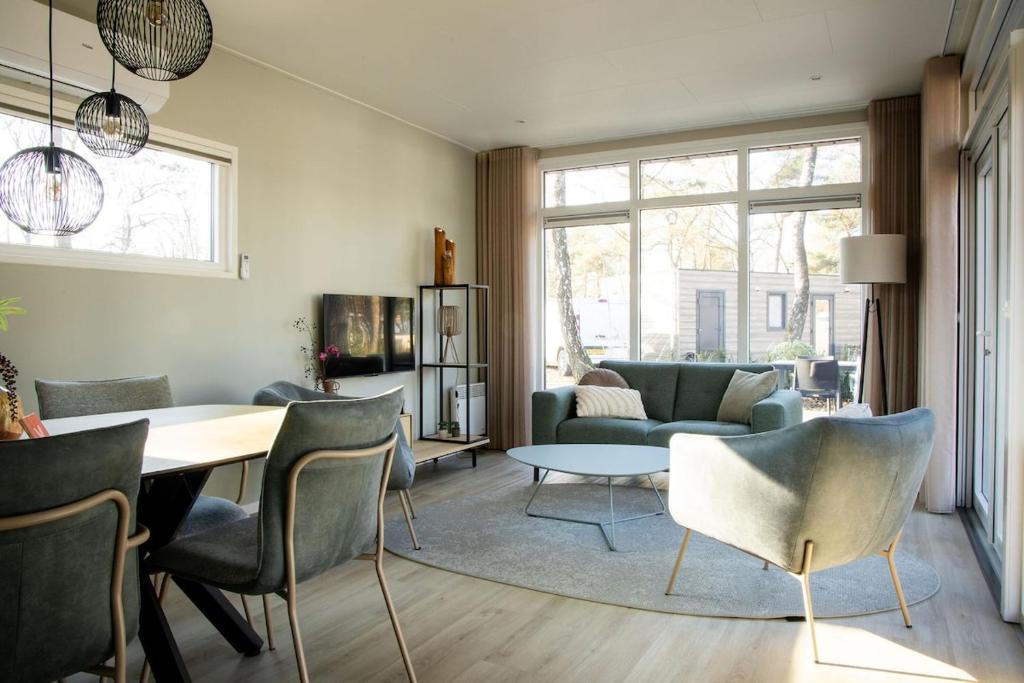 a living room with a couch and a table and chairs at Chalet Bosrijk in Haarle