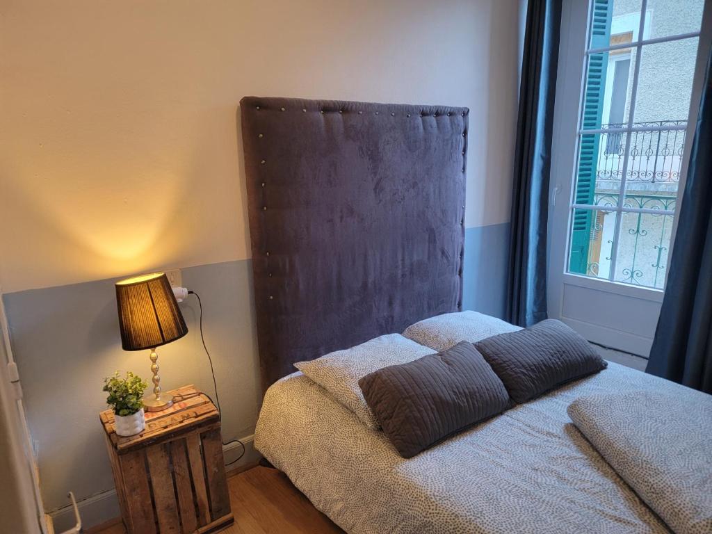 a bedroom with a bed with a large window at Chambre Lumineuse avec Balcon - Cuisine Partagée & Salle de Bain Privée in Lourdes