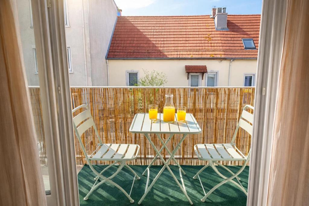 a table with glasses of orange juice on a balcony at Le Caballo - Appartement de charme à Digoin in Digoin