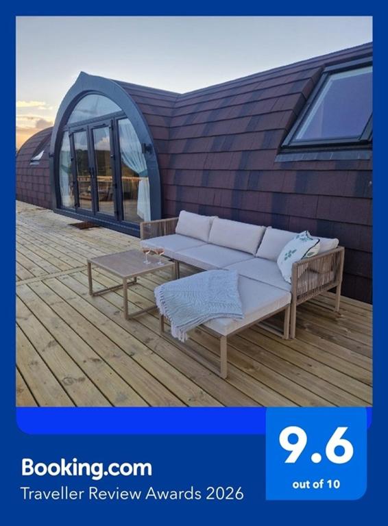 a couch and a table on a wooden deck at Bromach Lodge & NEW HOT TUB in Latheron