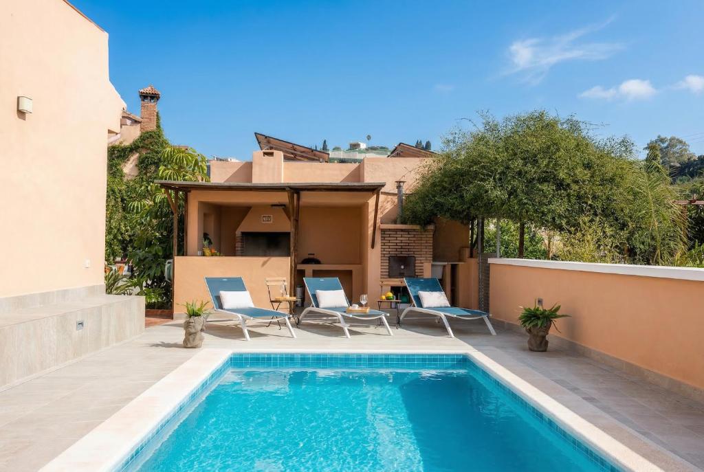 a swimming pool with chairs and a house at Comeback Villa Itaca in Motril