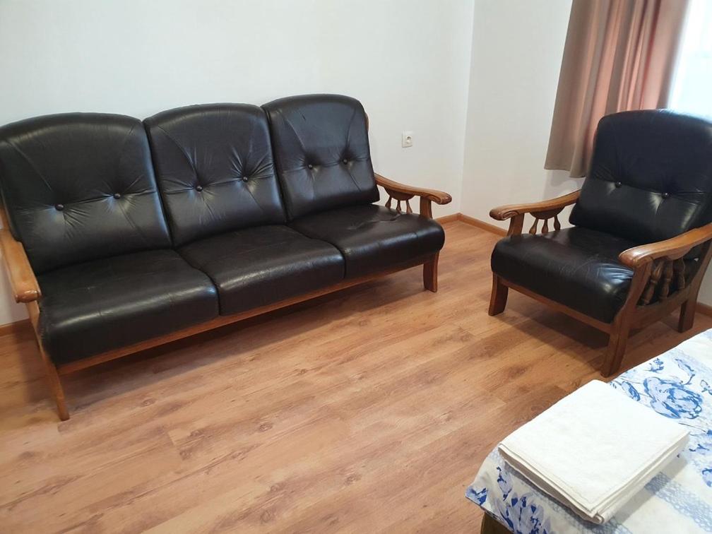 a black leather couch and two chairs in a living room at Kennedy House in Lyetnitsa
