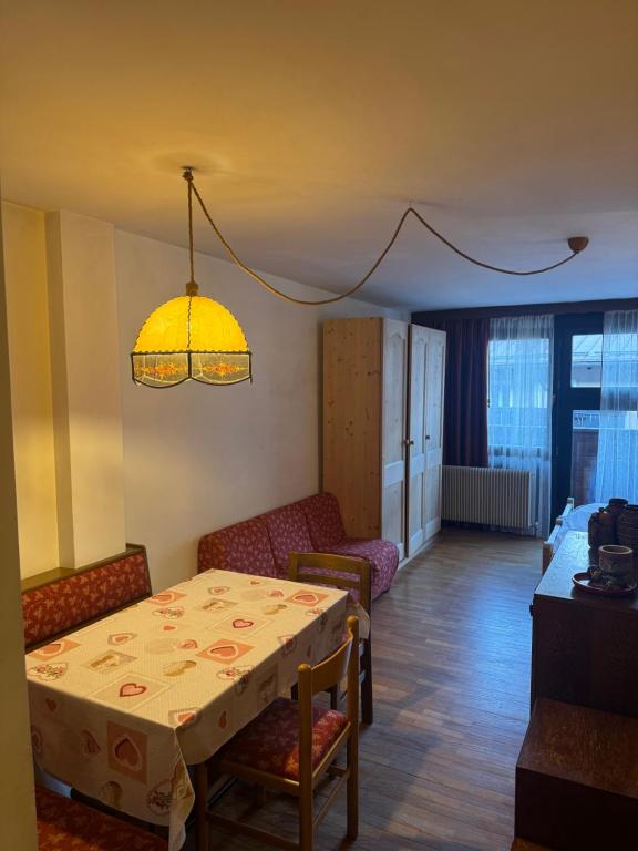 a dining room with a table and chairs and a lamp at Campiglio Monolocale Cima Tosa in Madonna di Campiglio