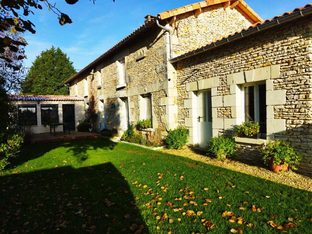 a stone house with a lawn in front of it at Les Lilas in Saint-Clair