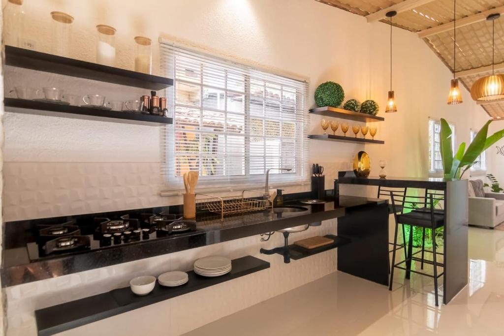 a kitchen with a black counter and a window at Golden Pipa House in Pipa