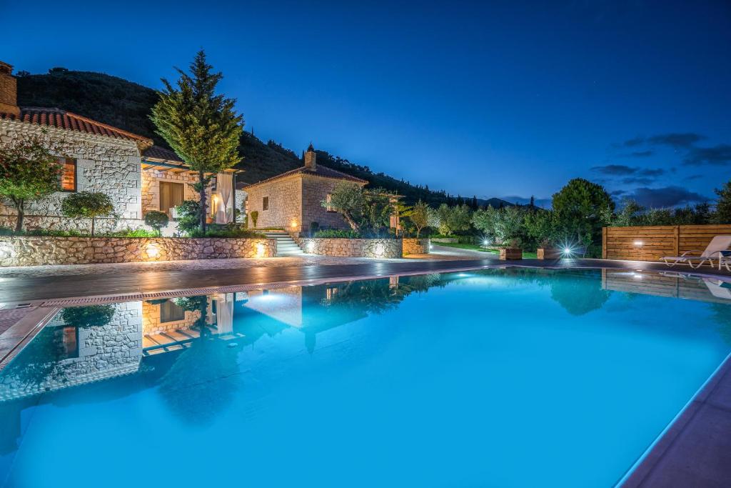 - une piscine en face d'une maison la nuit dans l'établissement San Antonio Villas, à Pandokrátor