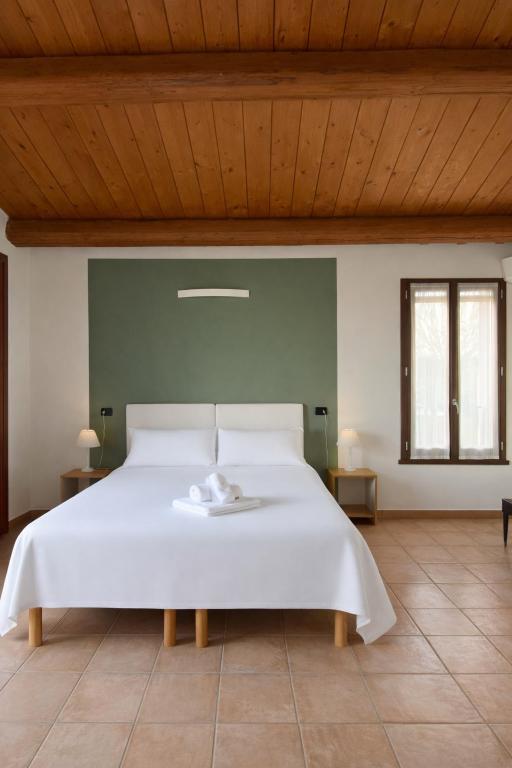 a large white bed in a room with two windows at Locanda Merlaschio in Faenza