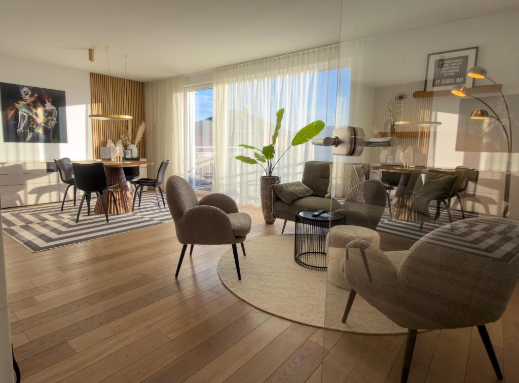 a living room with chairs and a dining room at "SONNENGRÜN" - Premium Apartments Seekirchen, Balkon in Seekirchen am Wallersee